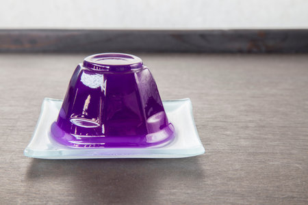 Purple grape jelly on dish on wooden background with copyspace