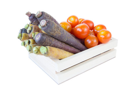 Many carrot and tomato with clipping path on wooden crate box isolated on white background with selective focusの写真素材