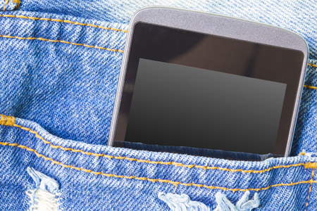 Mobile phone in the back pocket of blue jeans with copyspace macro backgroundの写真素材