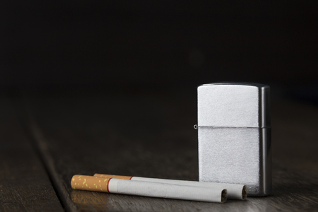 Lighter and two cigarette on old wooden table with low lightの写真素材