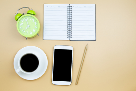 Notebook mobile phone calculator and black coffee white cup green clock on orange background pastel style with copyspace flatlayの写真素材