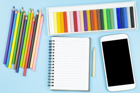 Crayon and book mobile phone topview flatlay on blue background pastel styleの写真素材