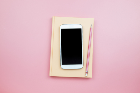 Cover notebook mobile phone pencil on pink background pastel style with copyspace flatlay topviewの写真素材