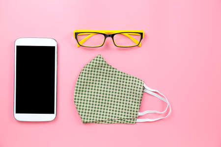 Green surgical mask plaid and yellow glasses with mobile clipping path screen
on pink backgroud pastel style flatlay topview copyspaceの写真素材