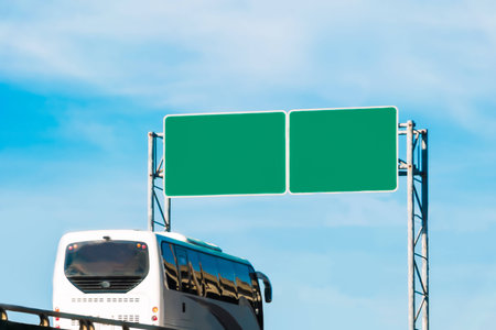 tourist bus and blank green traffic road sign on the sky backgroundの写真素材