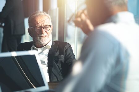 Senior businessman having a conversation with his colleague indoors.の写真素材