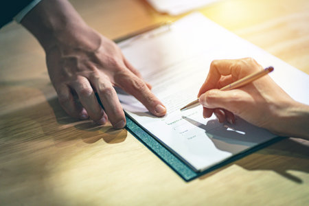 Closeup female hand signing a contract investment professional document agreement on the table with...