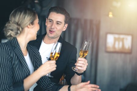 Man flirting on a woman while holding a glass of champagne at the bar.の写真素材