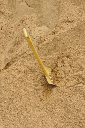  A shovel digging into pile of building sandの写真素材