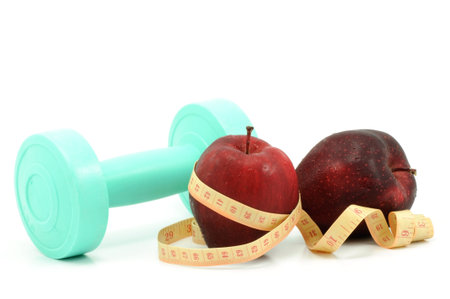 Fresh red apple with measuring tape and dumbbellの写真素材