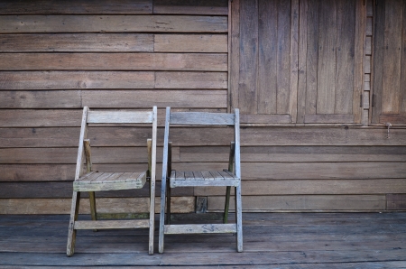 Old wooden chair against wooden wallの写真素材