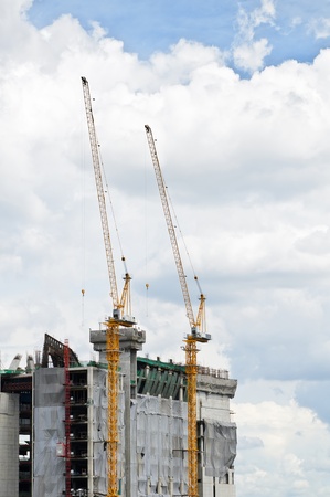 Building under construction and cranes under a cloudy sky backgroundの写真素材