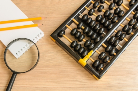 Ancient Chinese abacus,notebook,pencil,glass on wooden backgroundの写真素材