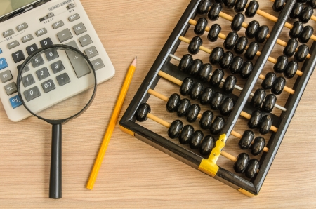 An old chinese abacus and modern calculator and pencil and glassの写真素材