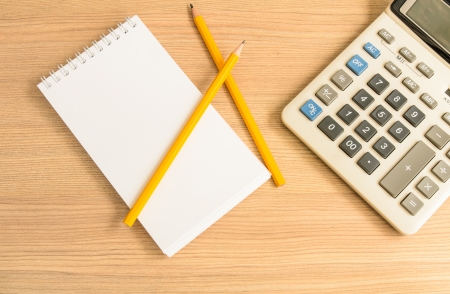 Calculator and notebook and pencil on wooden backgroundの写真素材
