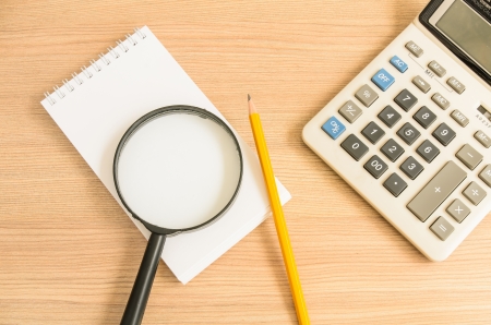 Calculator and notebook and pencil and glass on wooden backgroundの写真素材