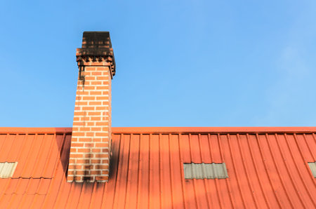 Brick chimney on the roof and blue skyの写真素材