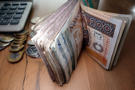 Financial wealth concept - polish bank rolls, coins and calculator on deskの写真素材