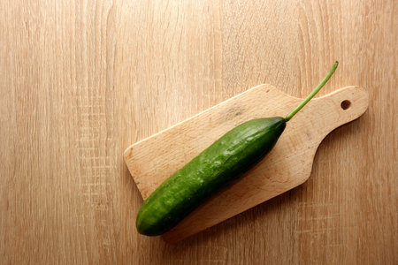 Fresh cucumber on wooden cutting board, copy space for your text or object