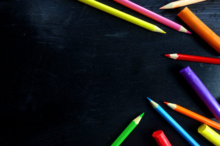 Back to school concept with colored pencils on chalkboard, view from overhead, copy space for your...
