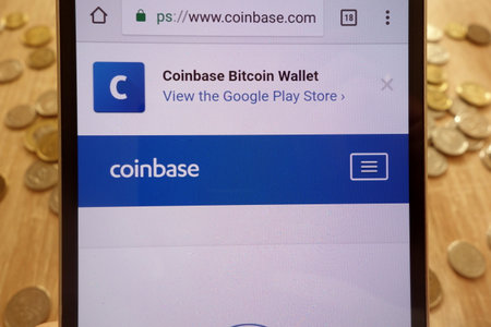 KONSKIE, POLAND - MAY 08, 2018: Coinbase cryptocurrency exchange website displayed on smartphone and stack of coinsのeditorial素材