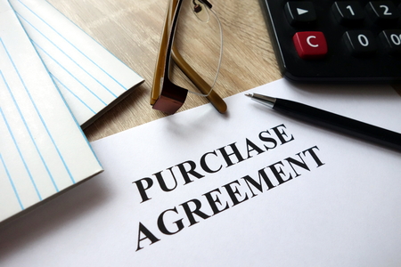 Purchase contract document with pen, calculator and glasses on deskの写真素材