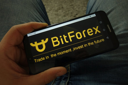 KONSKIE, POLAND - March 31, 2019: Man holding smartphone with BitForex cryptocurrency exchange logo
