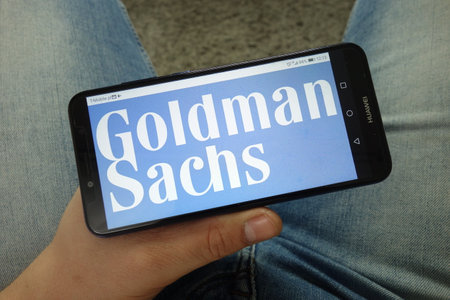 KONSKIE, POLAND - April 13, 2019: Man holding smartphone with Goldman Sachs company logoのeditorial素材