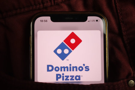 KONSKIE, POLAND - August 17, 2021: Dominos Pizza logo displayed on mobile phone hidden in jeans...
