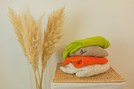 Pile of sweaters for cold autumn or winter weather on wicker basket