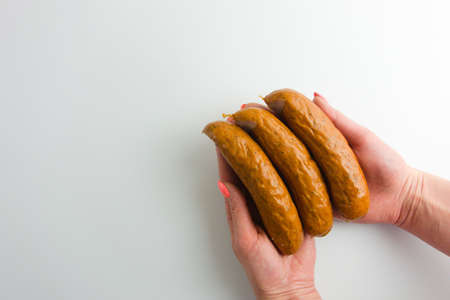 Female hands holding sausages ready to cook, fry or roast. Food preparation concept. White background with copy space for your designの写真素材