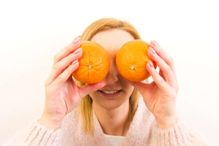 Close-up portrait of attractive healthy young woman holding oranges isolated on white background. Fruit diet, energy conceptsの写真素材