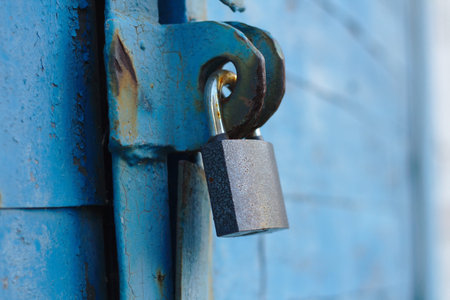 old padlock on a blue metal door with wooden planks cracked paint and rust