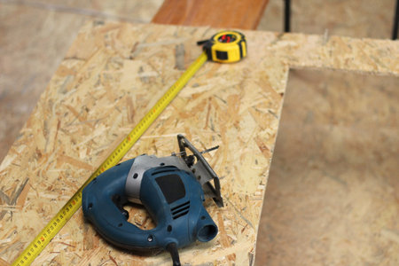 jigsaw, tape measure and pencil on osb plywood