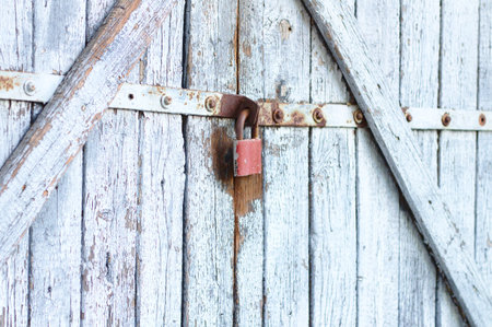 Old gray wooden plank gate with a padlock.