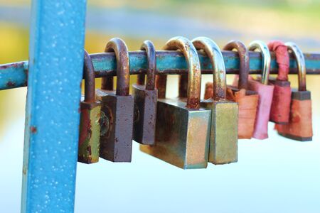 colored padlocks on the railing of the bridge over the riverの写真素材