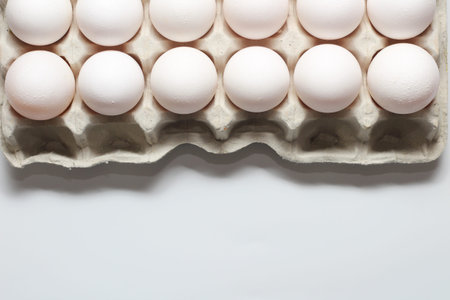 An isolated tray of eggs from recycled materials with white eggs on a white background. Top view