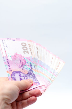 A banknote of 200 hryvnia in a male hand on a white background. Giving a bribe in Ukraine. European...