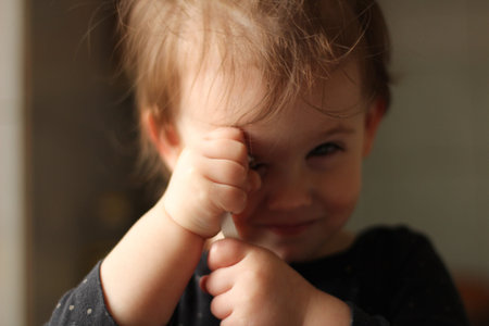 Close-up portrait of a little cute white baby with a dirty face in soft light and blurry background