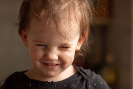 Close-up portrait of a little cute white baby with a dirty face in soft light and blurry backgroundの写真素材