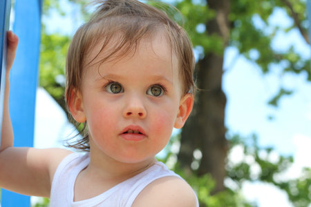 A piercing look of a little white girl with tousled hair outdoors. Little baby with very beautiful...