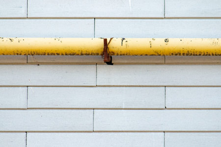 Smooth brick wall surface with a large yellow pipe at the top