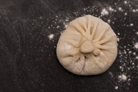 Raw Georgian cuisine dish khinkali on a black table. Top view