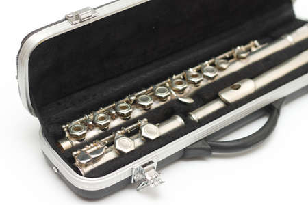 Partial side view of shiny disassembled silver flute in black case against white backgroundの写真素材