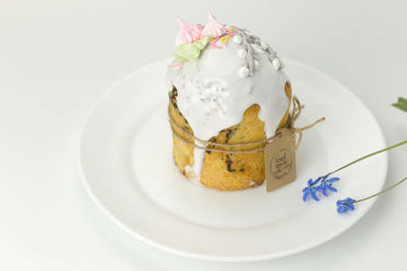 Orthodox Easter cake tied with a rope with a tag on a plate with spring flowers in a pot side view on a white backgroundの写真素材