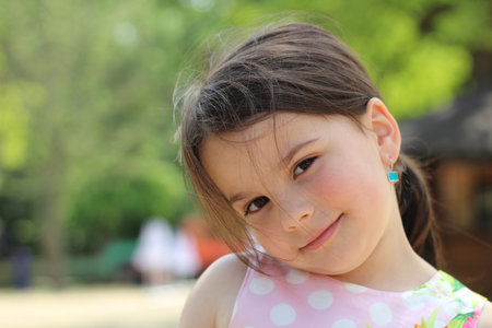 lovely smiling little girl with a tail in a sundress on the shore of a pondの写真素材