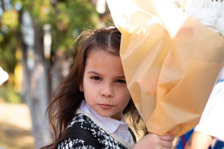 Little first-grader with a bouquet blows a kiss to her parentsの写真素材