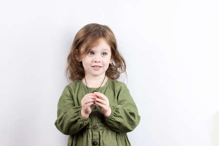 A small child with red hair, thinking, looks up and puts his hand to his head. Isolated photo of pensive girl on white backgroundの写真素材