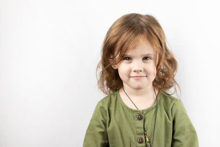 A small child with red hair, thinking, looks up and puts his hand to his head. Isolated photo of pensive girl on white backgroundの写真素材