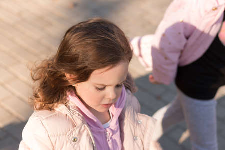 Little red-haired girl in an open jacket on a walk in the parkの写真素材